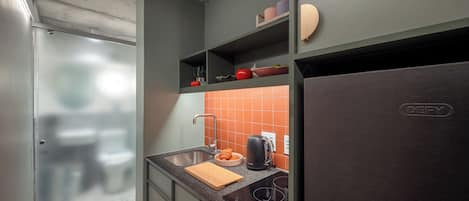 Cocina compacta con horno integrado, lavamanos y refrigerador.