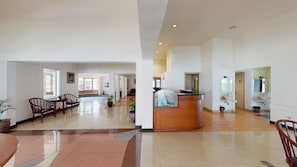 Un amplio vestíbulo con mostrador de recepción, zona de estar y vistas al pasillo.