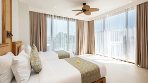 A hotel room with two beds, a ceiling fan, large windows with curtains, and a view of the city. - The Atma Bali (Denpasar)