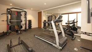 A gym with a treadmill, weight machines, and a mirror. - The Atma Bali (Denpasar)