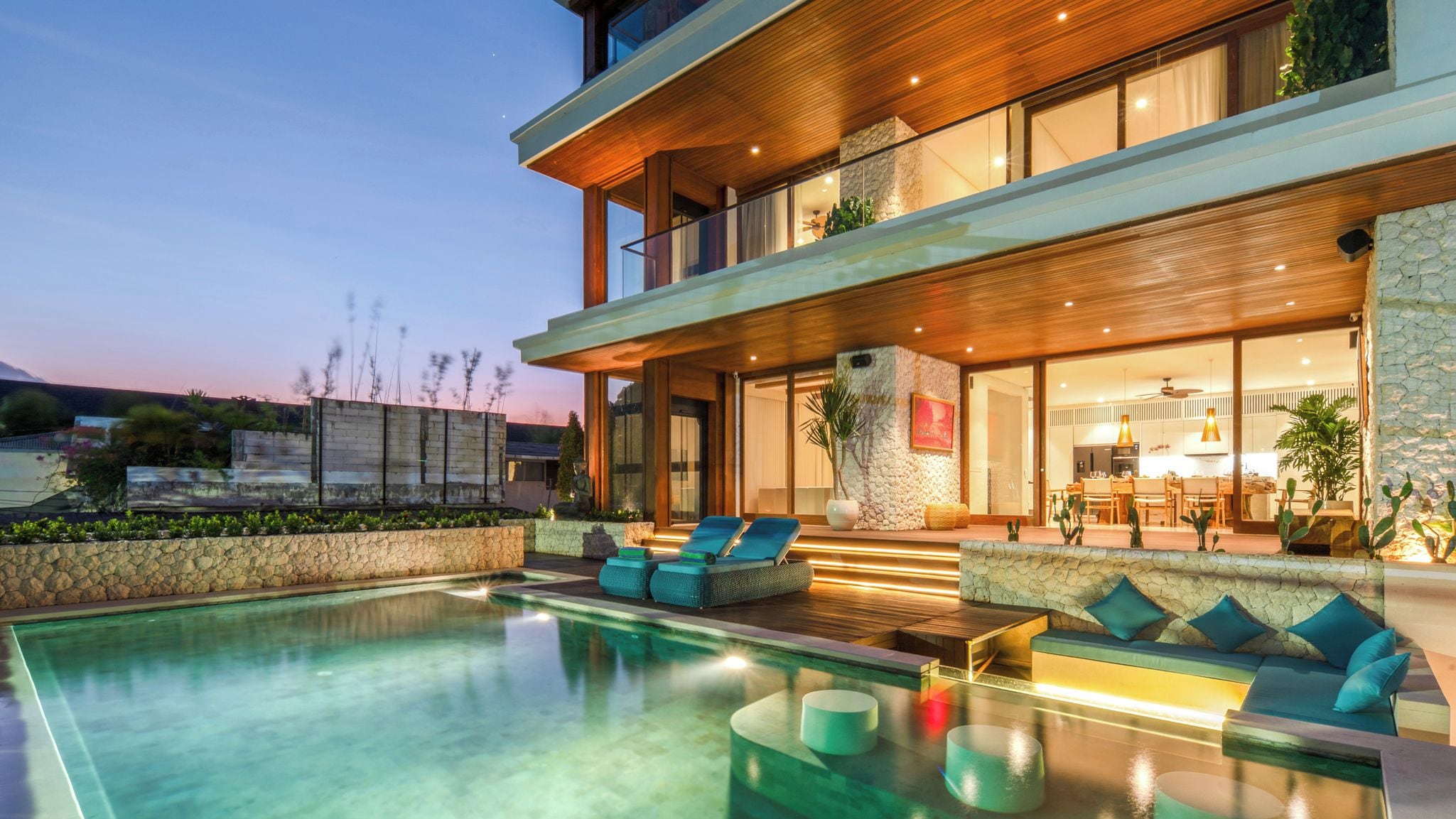 Une maison moderne à deux étages, dotée d’une piscine, d’un espace extérieur aménagé et d’une cuisine ouverte.