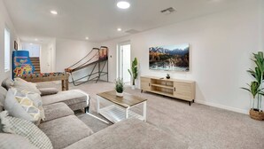 Sala de estar com sofá, mesa de centro, rack para TV e mesa de pebolim.