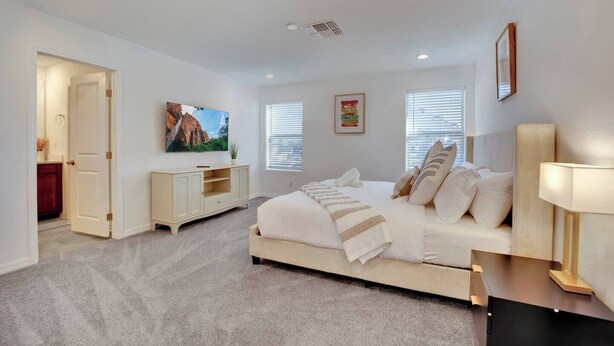 Quarto moderno com uma cama grande, mesa de cabeceira, televisão e janela com persianas.