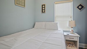 A bedroom with a bed, a nightstand, a lamp, and wall decorations. - Laketown Wharf 824 (Panama City Beach)