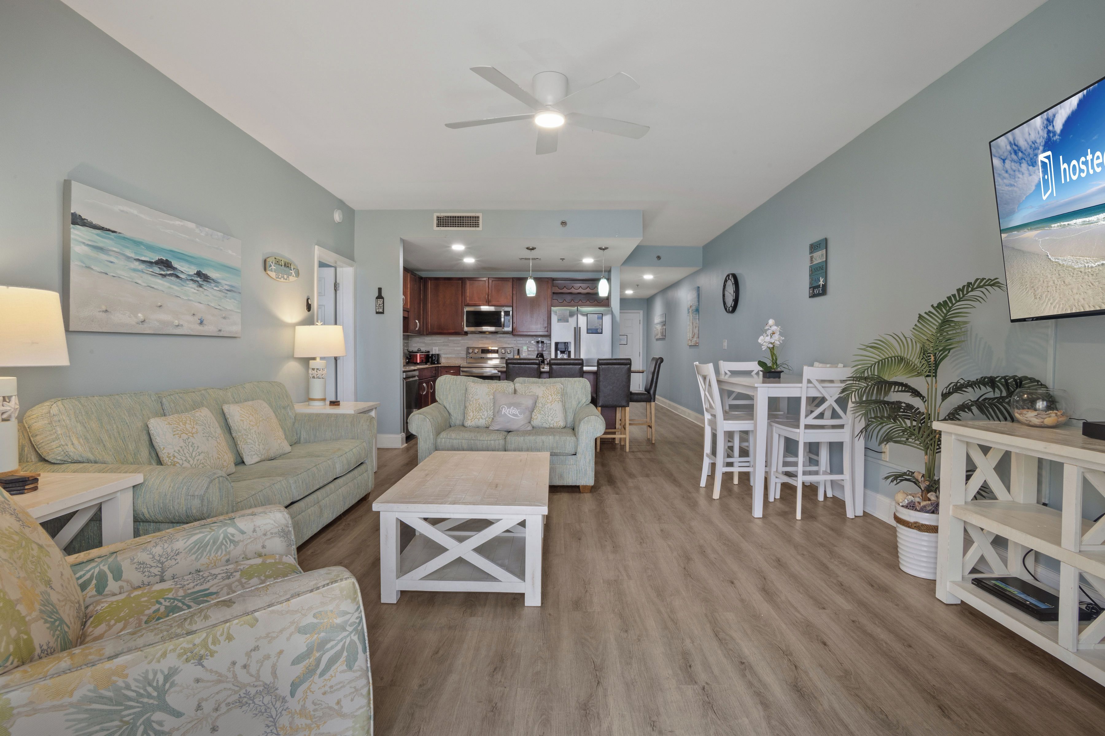 A spacious living area with a sofa, coffee table, and dining table. A kitchen is visible in the background.