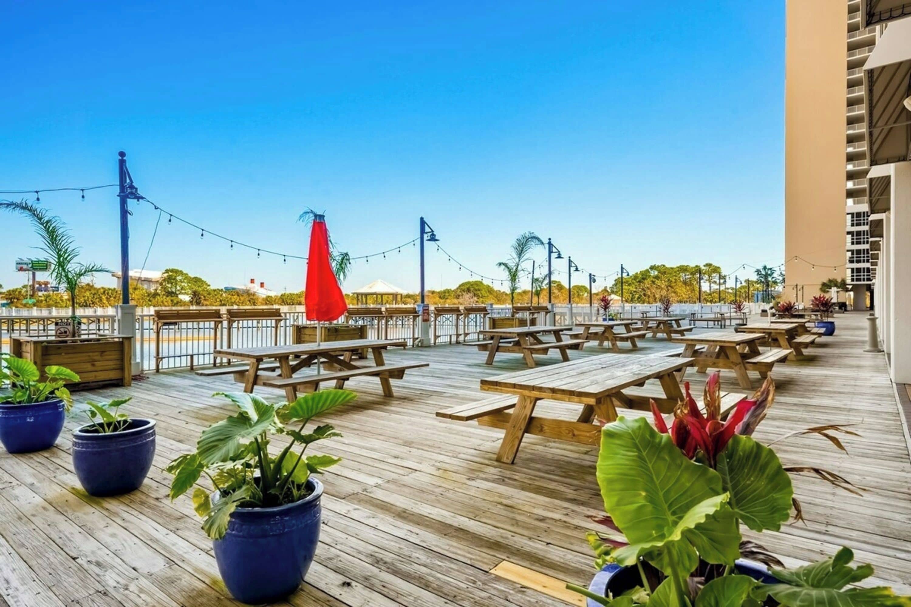 An outdoor deck with wooden picnic tables and potted plants.