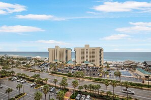 A high-rise hotel with a parking lot in front, a road with palm trees, and a beach in the background. - Laketown Wharf 824 (Panama City Beach)