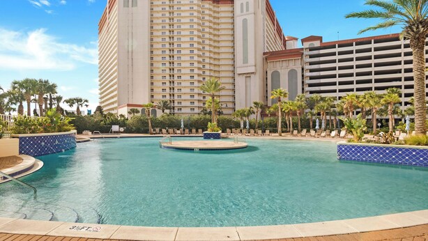 A hotel with a large pool, palm trees, and a multi-story building with balconies. - Laketown Wharf 824 (Panama City Beach)