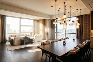 Una habitación de hotel moderna con un comedor amplio, sofás y vistas a la ciudad.