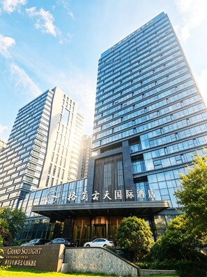 Un hotel moderno con fachada de vidrio, varios pisos y una entrada destacada.