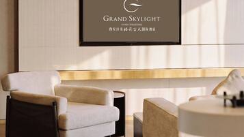 A modern hotel lobby with a reception desk, seating area, and a framed sign above.