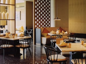 A restaurant interior with tables, chairs, and a decorative wall.
