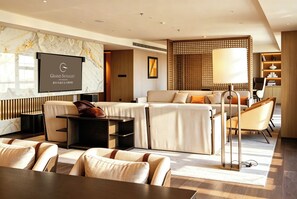 Een moderne hotelkamer met een marmeren wand, een televisie, een zithoek, een salontafel en een vloerlamp.