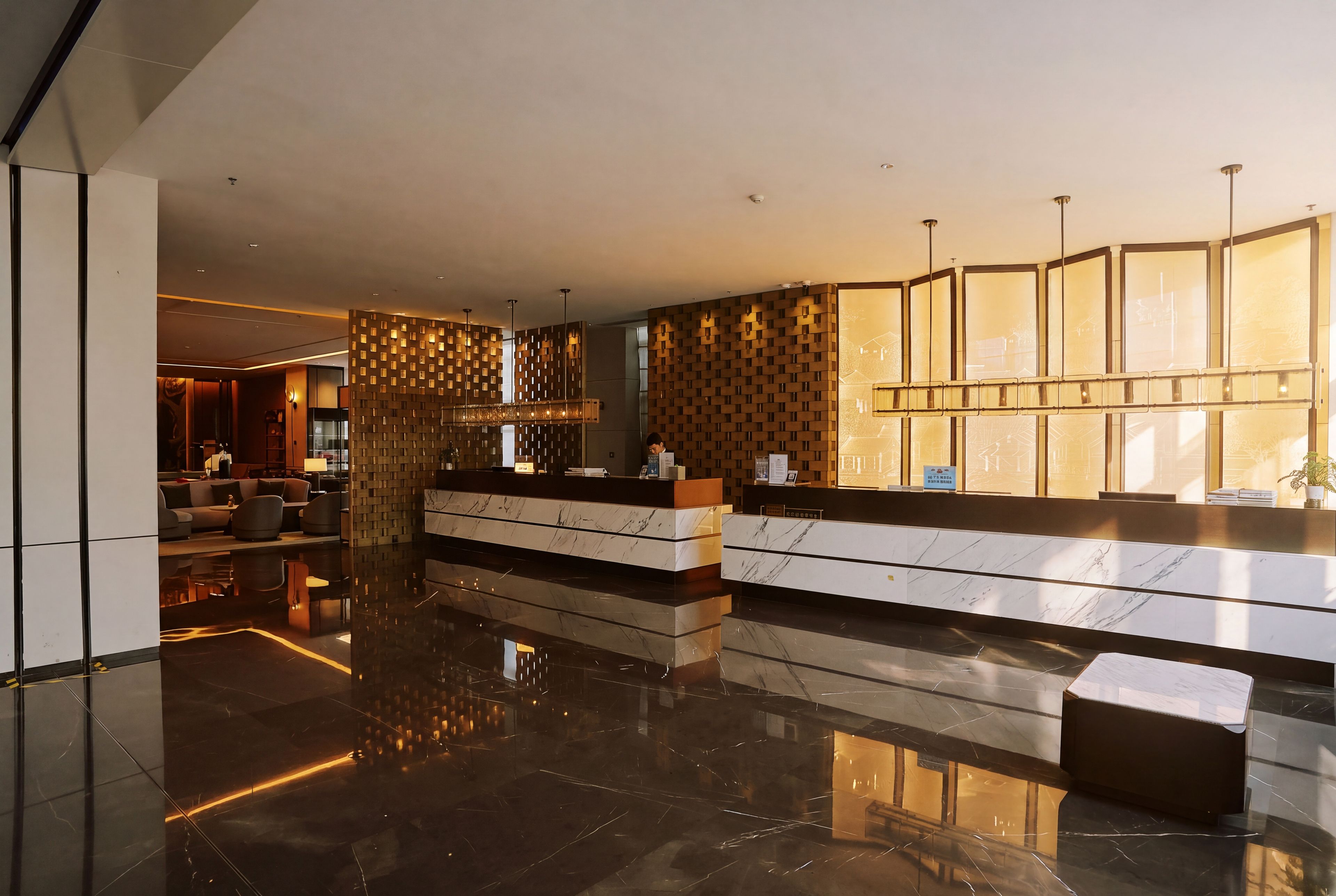 A modern hotel lobby with a reception desk, seating area, and a decorative wall.