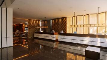 A modern hotel lobby with a reception desk, seating area, and a decorative wall.
