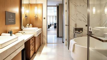 A modern bathroom with two sinks, a large bathtub, and a glass shower enclosure.