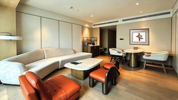 A modern living room with a sofa, chairs, a coffee table, and a dining area with a small table and chairs.