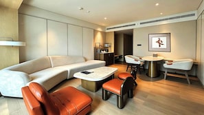 Una sala de estar moderna con sofá, sillones, una mesa de centro y un comedor con una mesita y sillas.