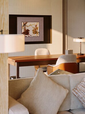Habitación de hotel con una mesa de comedor, un sofá, una obra de arte enmarcada en la pared y una lámpara.