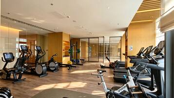 A modern gym with various cardio and strength training equipment, including treadmills, stationary bikes, and weight machines.