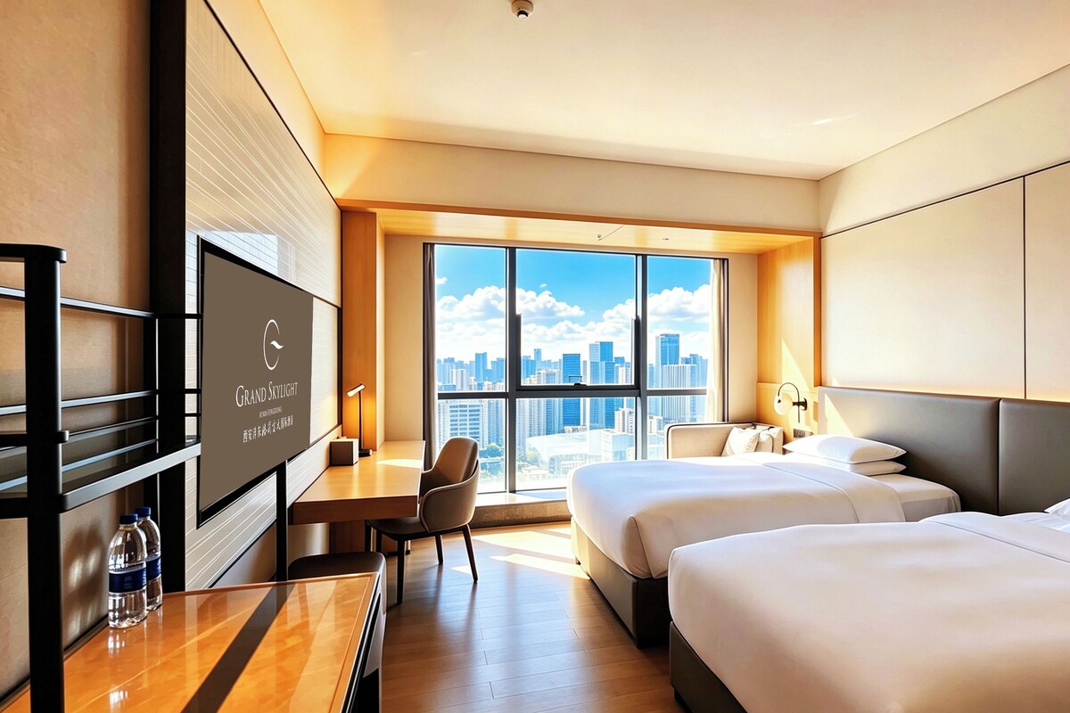Habitación de hotel con vistas a la ciudad, dos camas, un escritorio, una silla y un televisor.