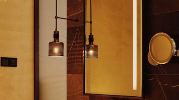 A modern bathroom with a large mirror, two pendant lights, a white sink, and a towel rack.