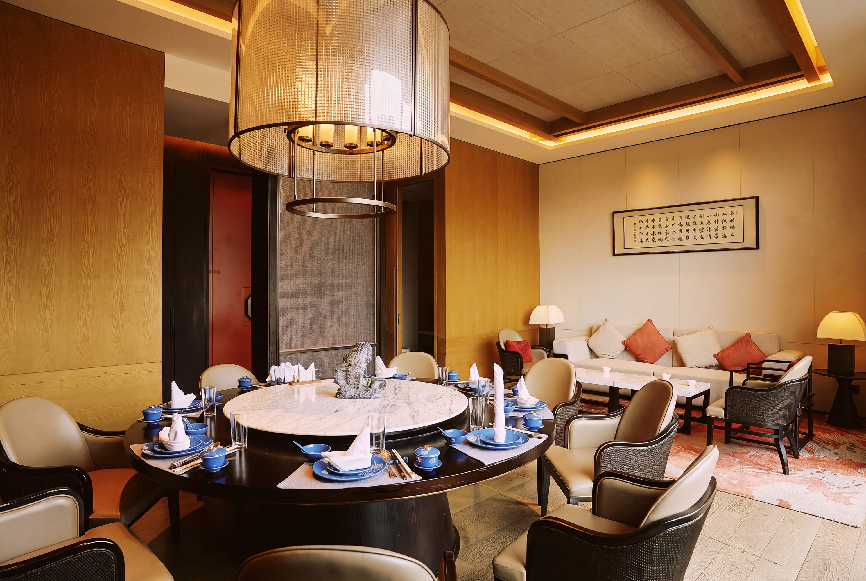 Ein Essbereich eines Hotels mit einem runden Tisch, gedeckt für eine Mahlzeit, umgeben von Stühlen und einer Couch im Hintergrund.