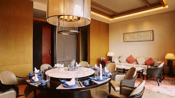 Ein Essbereich eines Hotels mit einem runden Tisch, gedeckt für eine Mahlzeit, umgeben von Stühlen und einer Couch im Hintergrund.