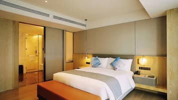 Una habitación de hotel con una cama, mesitas de noche, un banco y un vestidor.