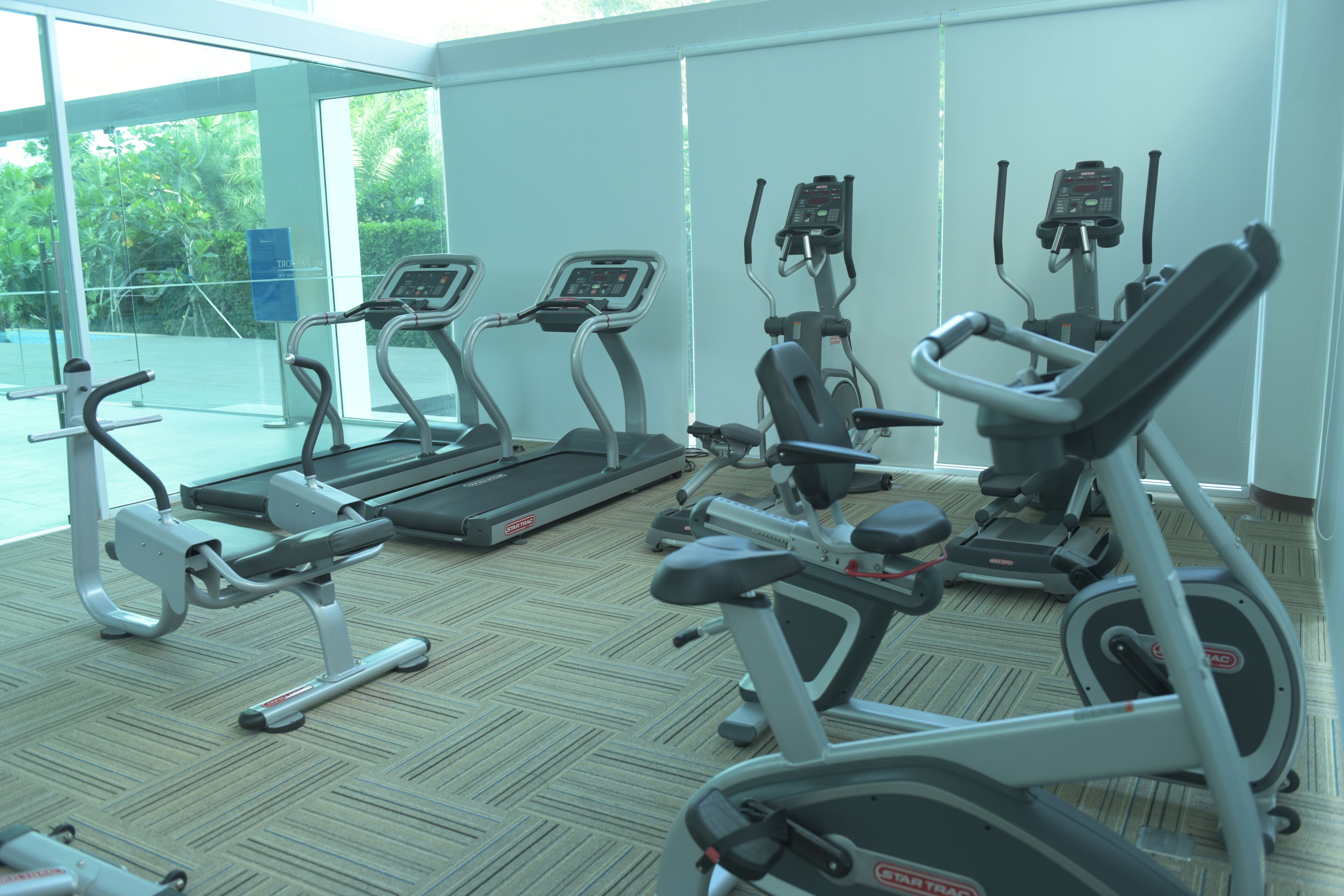 A gym with various exercise equipment including treadmills, stationary bikes, and elliptical machines.