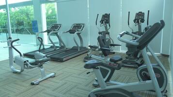 A gym with various exercise equipment including treadmills, stationary bikes, and elliptical machines.