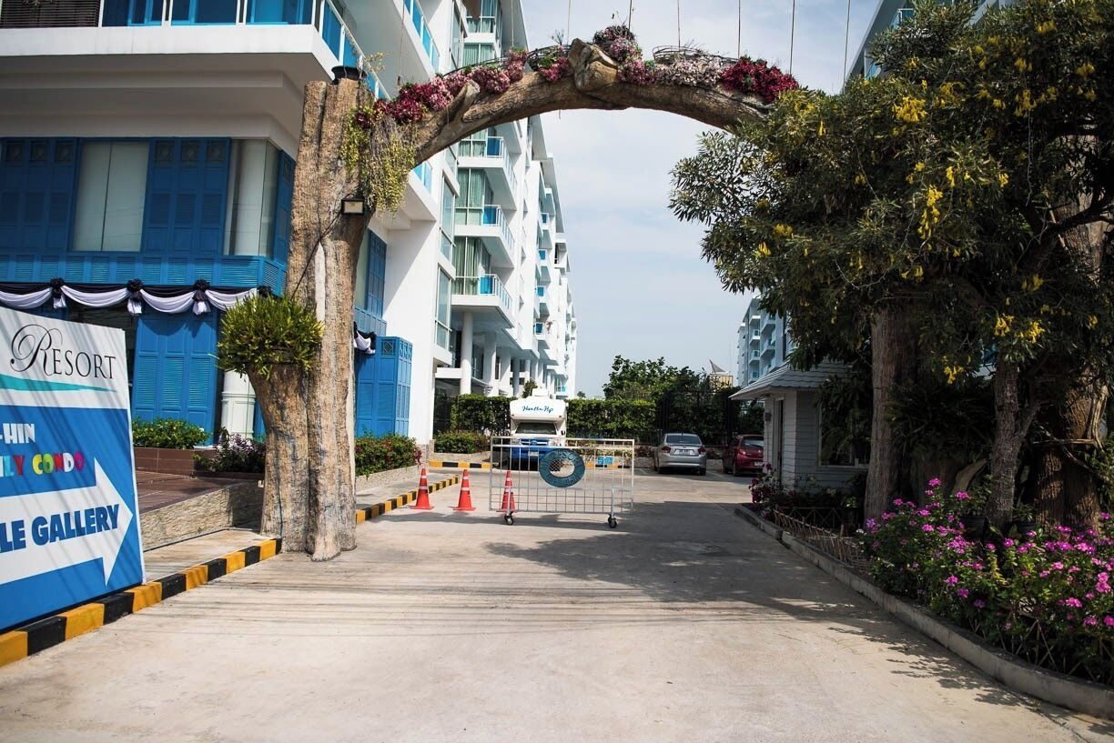 A hotel entrance with a decorative archway, a sign for a gallery, and a vehicle in the background.