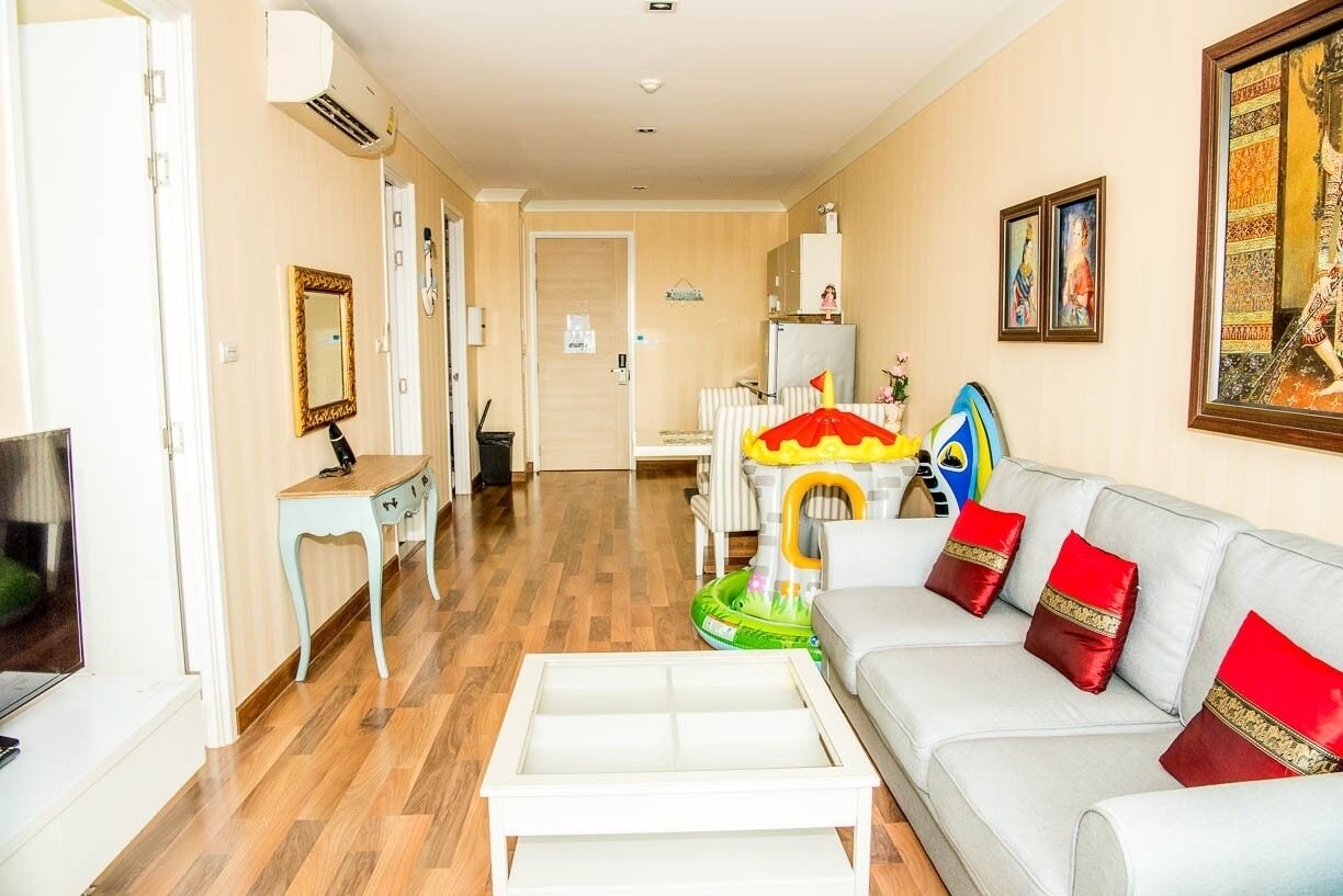 Ein Wohnzimmer mit einer Couch, einem Fernseher, einem kleinen Tisch und einem bunten Spielbereich für Kinder.