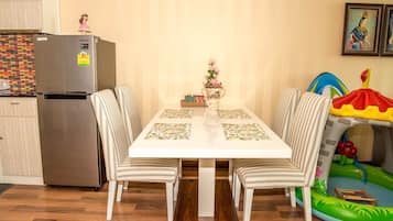 A dining area with a white table, striped chairs, a refrigerator, and a small play area with a slide and inflatable pool.
