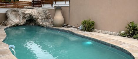 A swimming pool with a rock feature and a large vase.