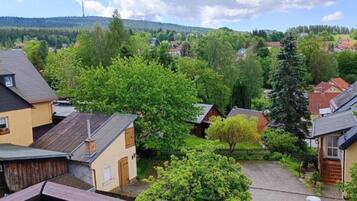 A residential area with houses, trees, and a hilly landscape in the background.