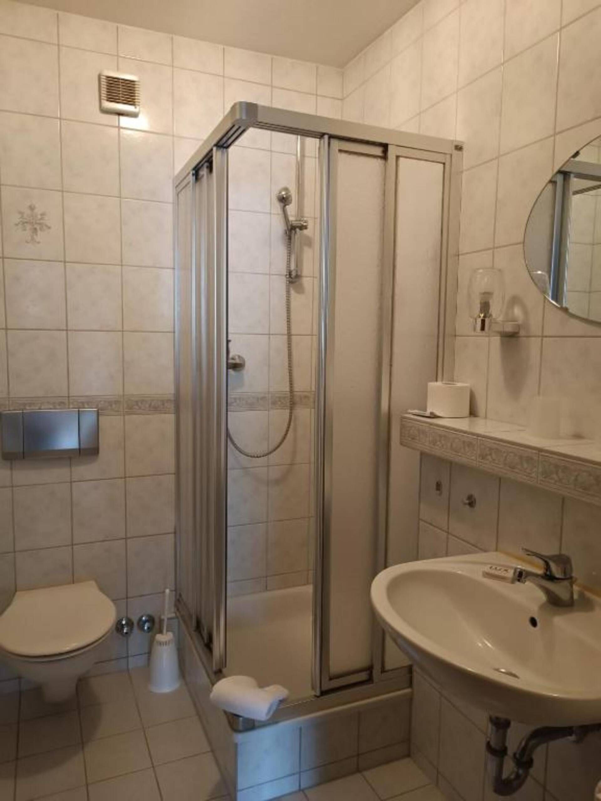 Un bagno con box doccia, toilette, lavandino e specchio.