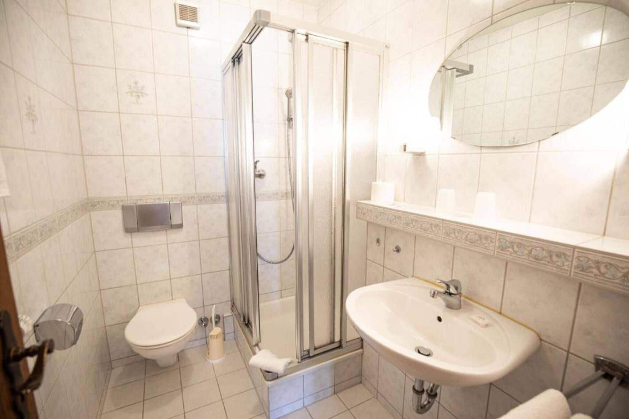 Ein Badezimmer mit einer Duschkabine, einer Toilette und einem Waschbecken mit Spiegel.