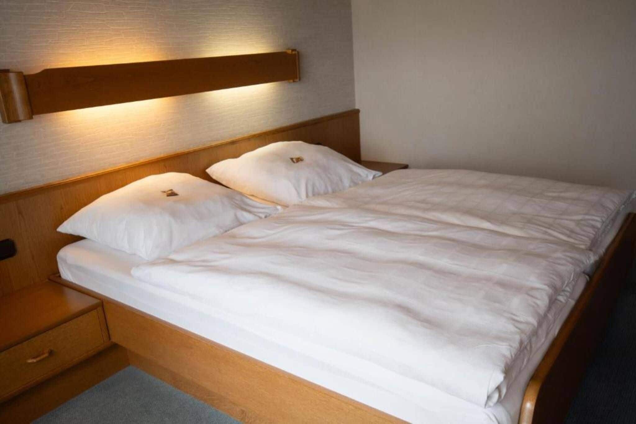 Ein ordentlich bezogenes Bett mit weißen Leinen in einem Hotelzimmer.