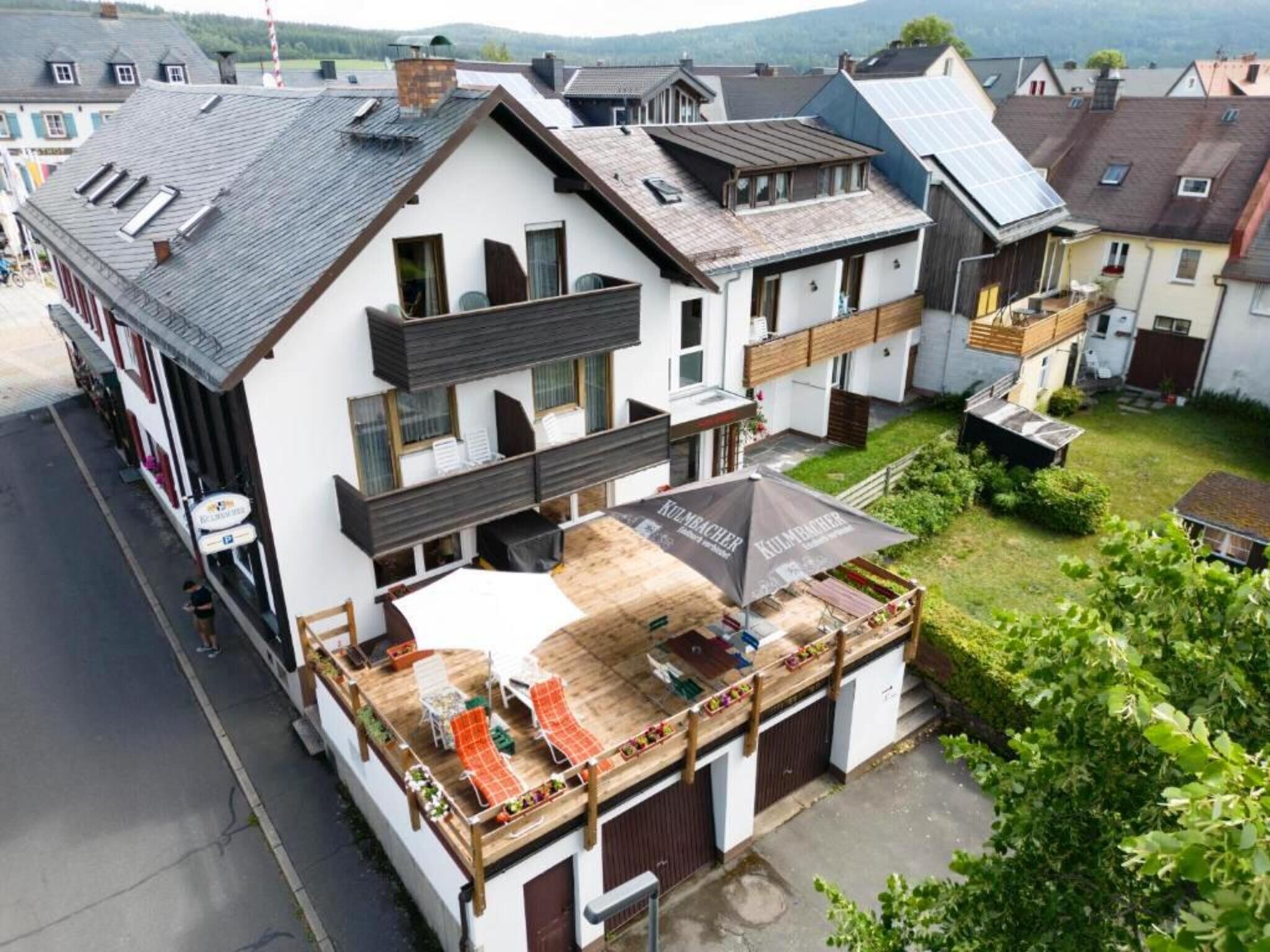 A multi-story building with a covered outdoor seating area, a garage, and a view of the surrounding neighborhood.