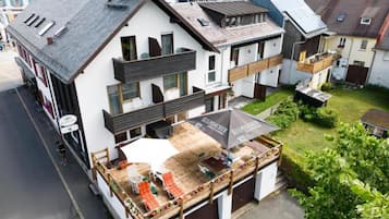 A multi-story building with a covered outdoor seating area, a garage, and a view of the surrounding neighborhood.