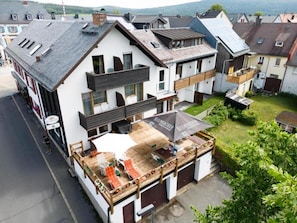 A multi-story building with a covered outdoor seating area, a garage, and a view of the surrounding neighborhood. - Landhotel Jägerhof (Bischofsgrün)
