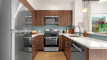 A modern kitchen with stainless steel appliances, wooden cabinets, and a view of the outdoors.