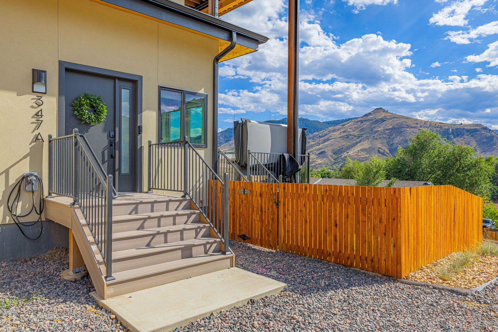 A modern building with a wooden fence, a staircase leading to a door, and a view of mountains in the background.