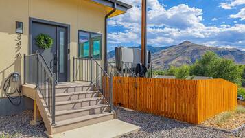 A modern building with a wooden fence, a staircase leading to a door, and a view of mountains in the background.