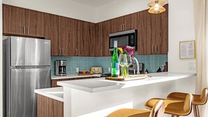 A modern kitchen with wooden cabinets, a stainless steel refrigerator, a coffee maker, a toaster, and a bar area with stools. - Hot Tub, Mt Views, Luxury New build in Golden (Golden)