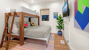 A bedroom with a bunk bed, a ladder, a potted plant, a TV, and artwork on the wall. - Hot Tub, Mt Views, Luxury New build in Golden (Golden)