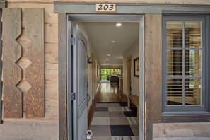 A wooden exterior with a number '203' above a door, leading into a hallway with a checkered floor. - White River Condo 203 at South Grand Lodge | 3BR with Partial Mt. Hood View (Government Camp)
