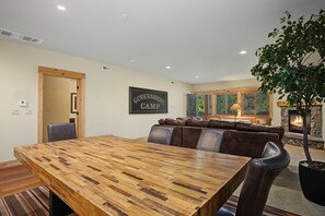 A dining area with a wooden table and chairs, a living room with a fireplace, and a sign that reads 'GOVERNMENT CAMP'. - White River Condo 203 at South Grand Lodge | 3BR with Partial Mt. Hood View (Government Camp)