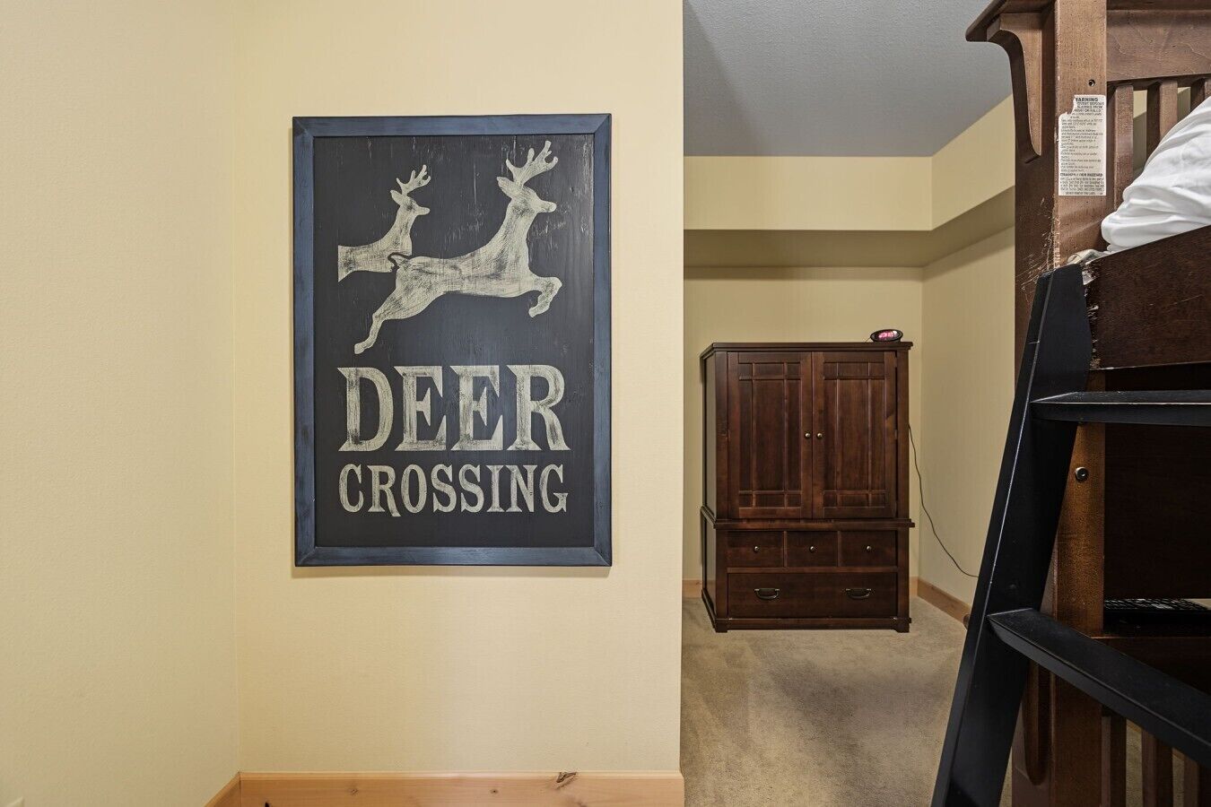 Un letrero enmarcado con siluetas de ciervos y el texto 'DEER CROSSING'.